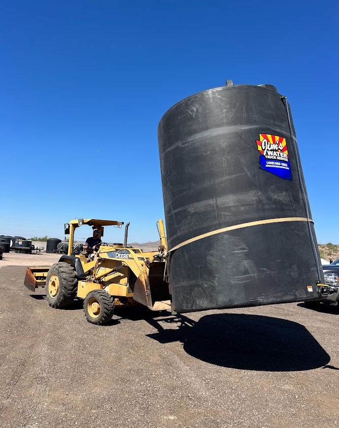 5,000-gallon water tank being moved by loader at Jim's Water Truck Service yard